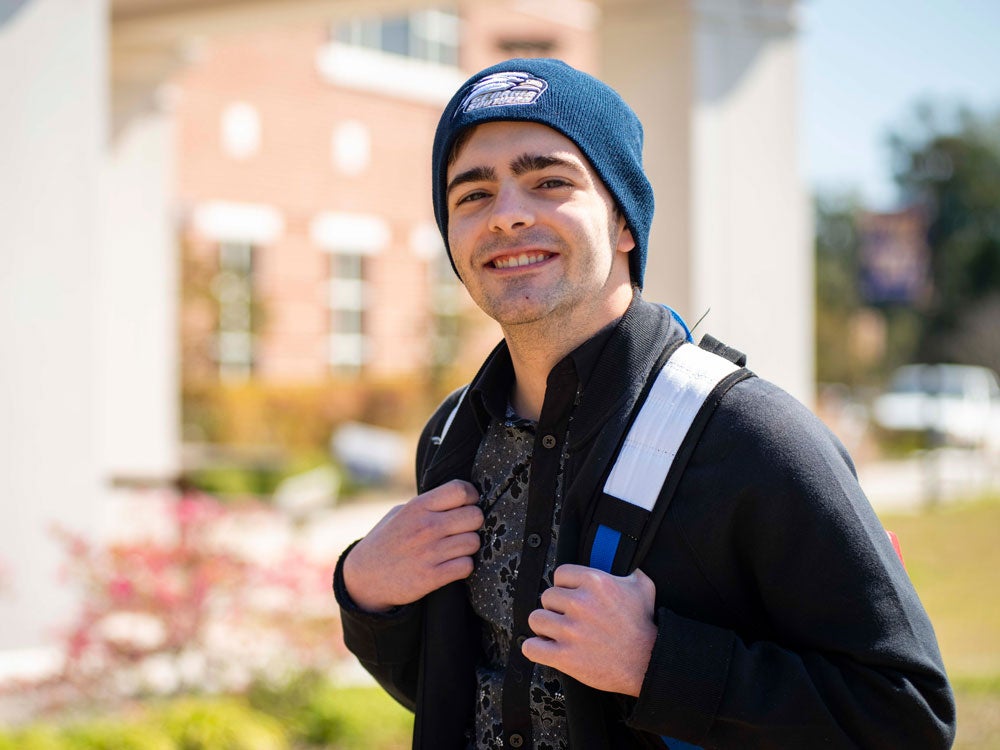 A student with a backpack smiles while walking into Georgia Southern's Liberty Campus