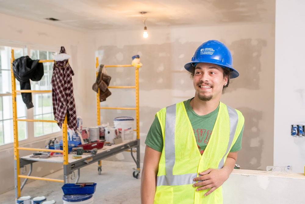 A student from Georgia Southern's M.S. in Civil Engineering program wears a hi-viz vest and hard hat to walk through a building site