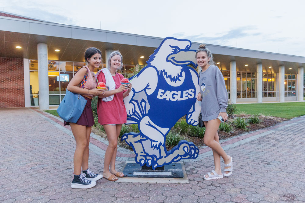 Three Georgia Southern students stand near Georgia Southern's mascot while holding snow cones