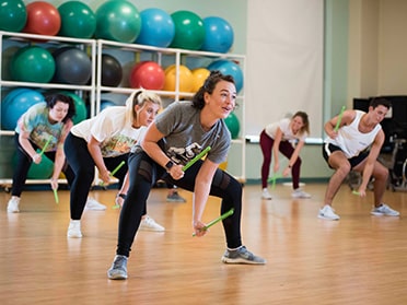 Students participate in an energetic fitness class using weighted drumsticks to pound the floor.