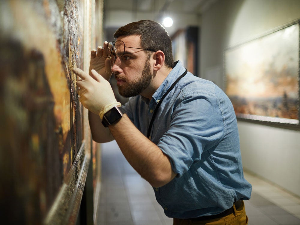 Georgia Southern student examining oil on canvas art display, hands on experience with art history features