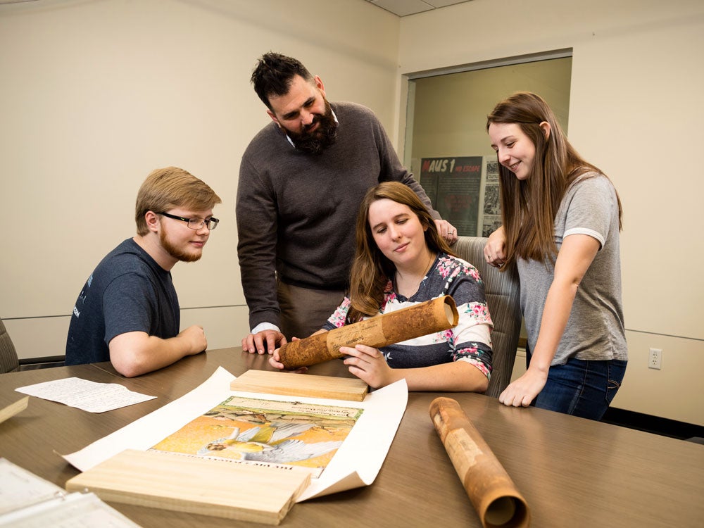 Group of Georgia Southern Students studying historical documents and artifacts at a table together, working on history project