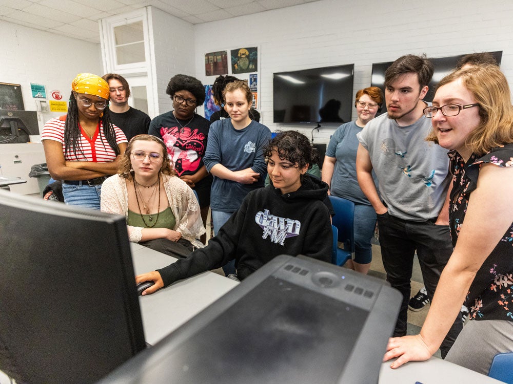 group of students admiring a digital design of a georgia southern student, in art class