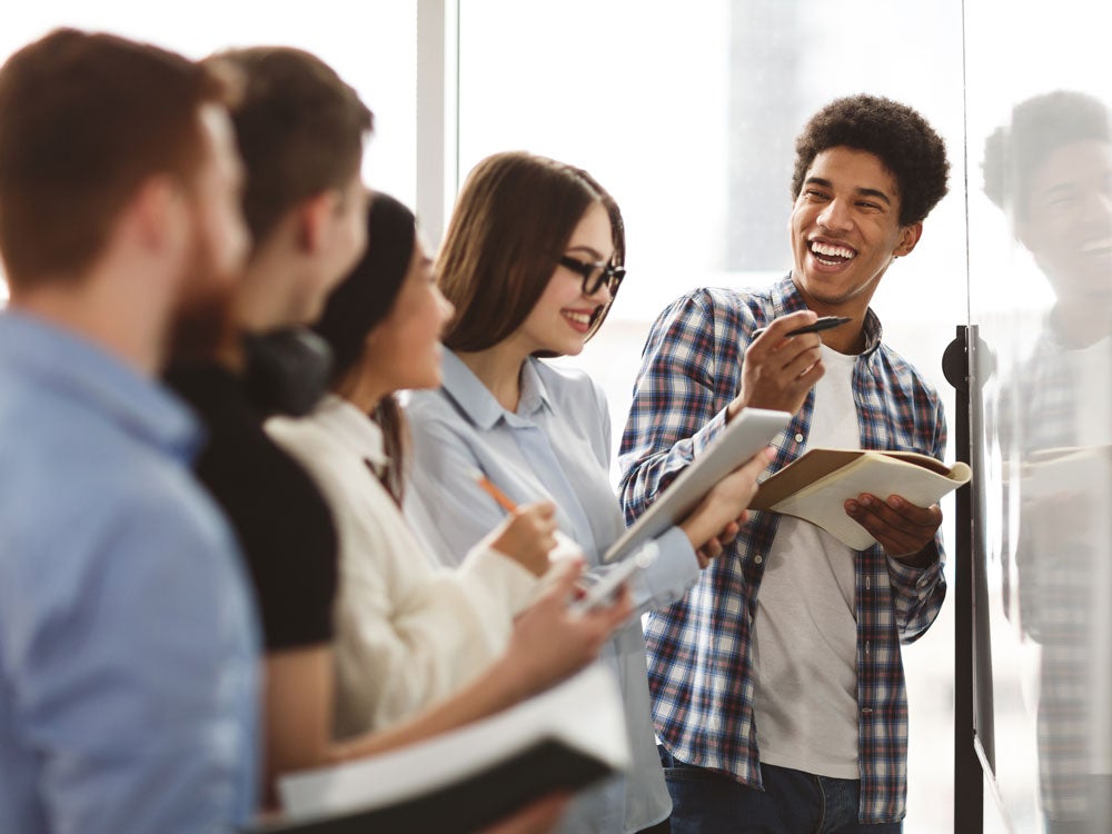 group of georgia southern students conversing at white board, planning speech