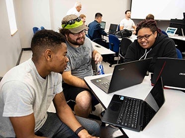 Sitting around a table with laptops, three Georgia Southern B.S. in Computer Science students meet up for a study session