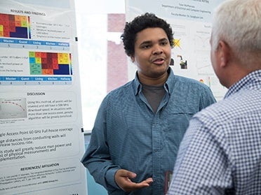 Standing by his presentation, a student from Georgia Southern's B.S. in Electrical Engineering program discusses his research during the Department's annual symposium