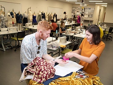 Two Georgia Southern B.S. in Fashion Merchandising and Apparel Design students share supplies and fabrics in a design studio