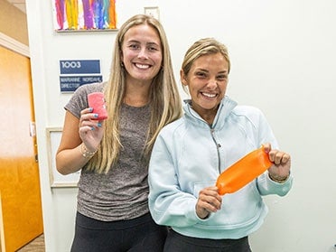 Two Georgia Southern B.S. in Human Development and Family Science students smile while holding first aid supplies