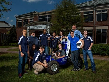 Standing outside the College of Engineering building, students from Georgia Southern's B.S. in Mechanical Engineering program show off their vehicle designed for an SAE competition