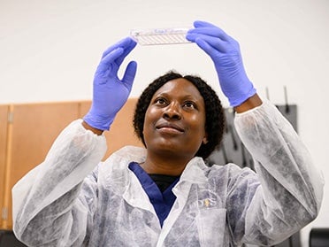 A student in Georgia Southern's B.S. in Medical Laboratory Science program wears a cleanroom suit and gloves to analyze a sample