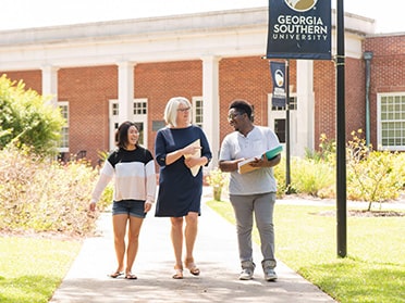 Two B.S. in Nutrition and Food Science students in Georgia Southern's Honors College walk and talk outdoors with a faculty member