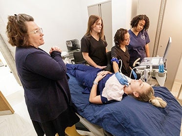 Practicing on a student, three B.S. in Radiologic Sciences, Diagnostic Medical Sonography students at Georgia Southern receive instruction on performing ultrasounds.