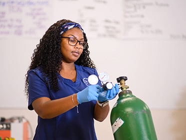 A student from Georgia Southern's B.S. in Respiratory Therapy program practices reading a gauge on an oxygen tank ahead of a practicum assignment