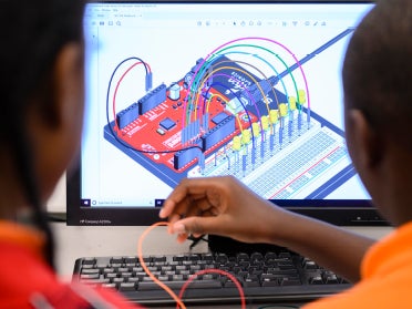 two students in front of a computer rendered model