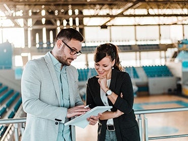 Standing near a basketball court, an intern from Georgia Southern's B.S. in Sport Management program reviews notes with their mentor