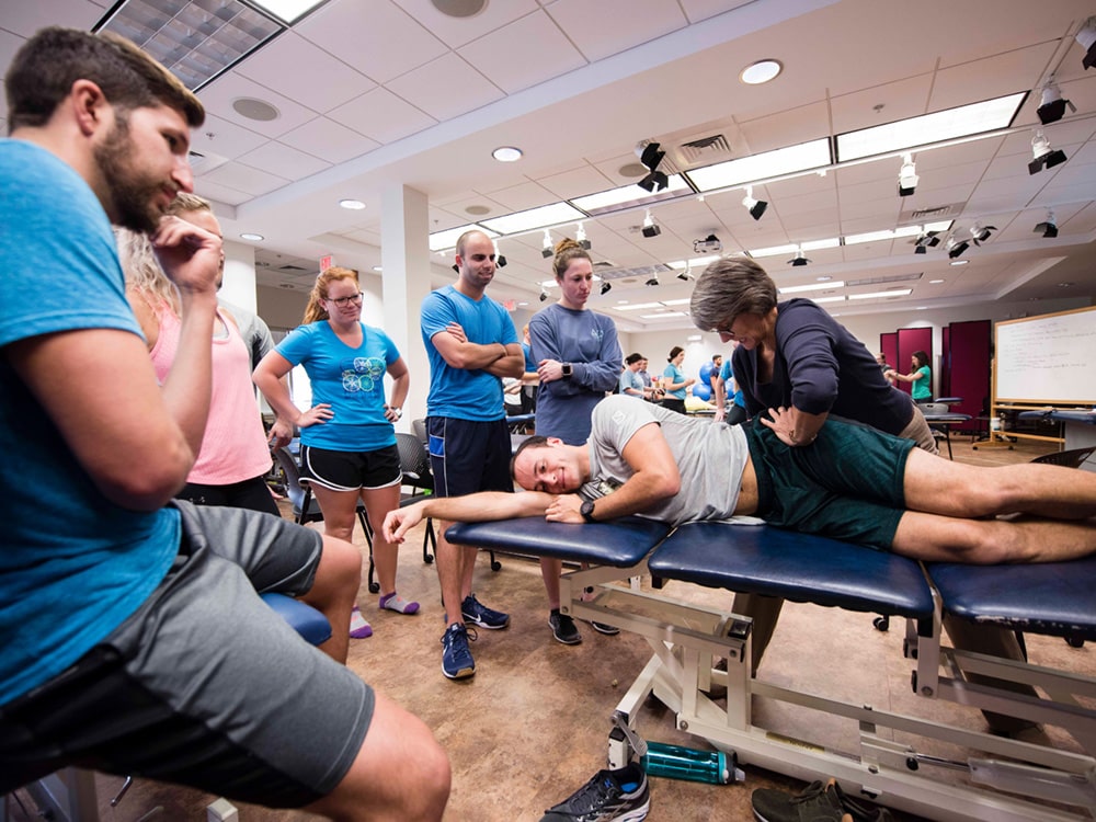 A Georgia Southern DPT professor instructs a group of students to perform a passive maneuver on a student-patient.