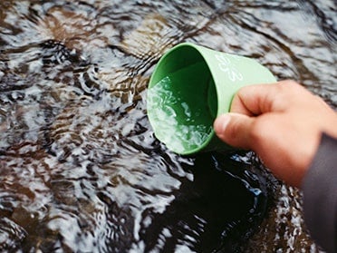 A student from Georgia Southern's Department of Biostatistics, Epidemiology and Environmental Health Sciences uses a cup to collect a water sample for analysis