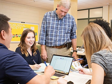 A professor meets with students from Georgia Southern's M.A. in Social Science program working on a group project