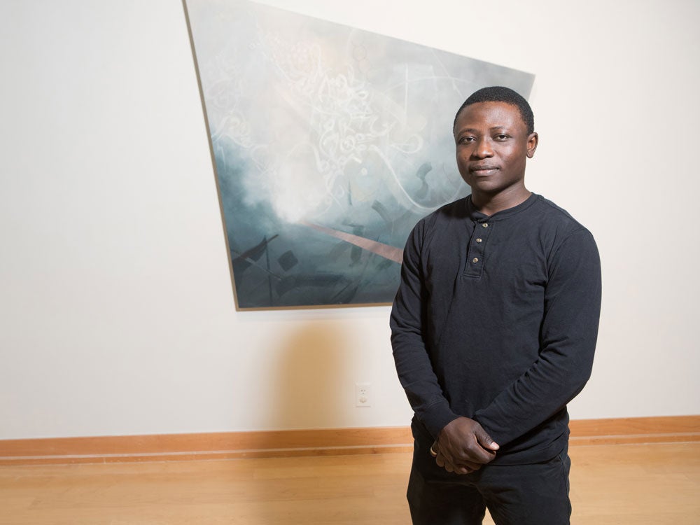 georgia southern student in front of art display, featuring paint on canvas