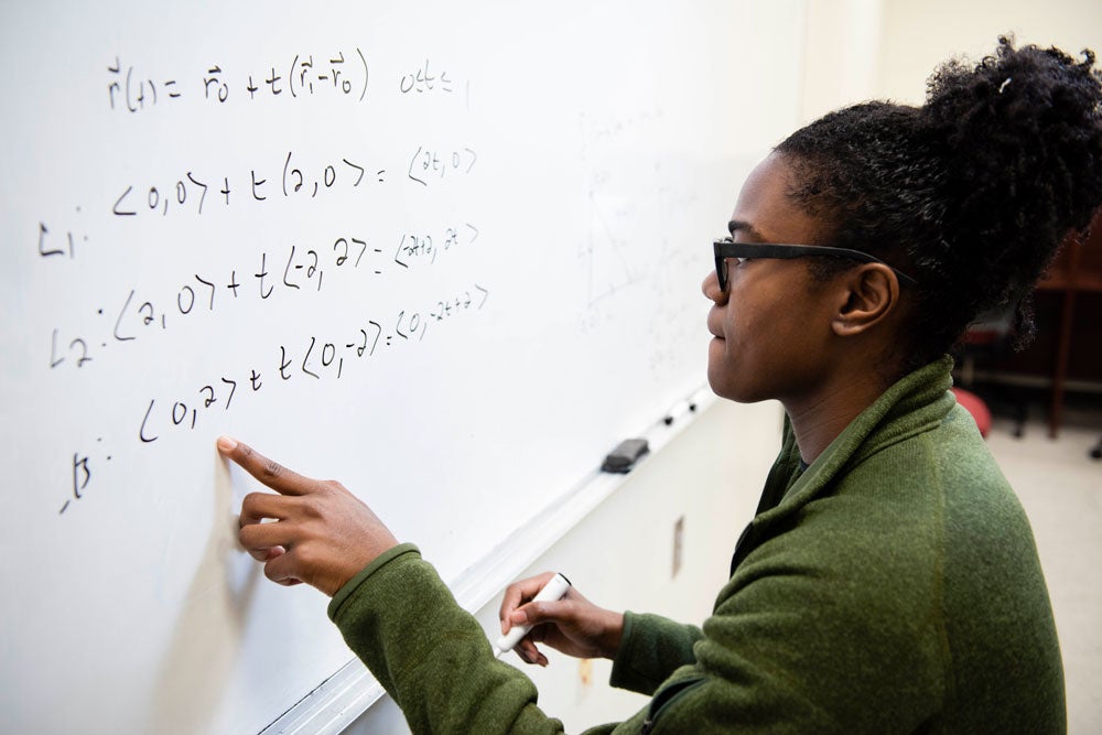 A student from Georgia Southern's M.S. in Mathematics program writes an equation on a whiteboard while contemplating its significance