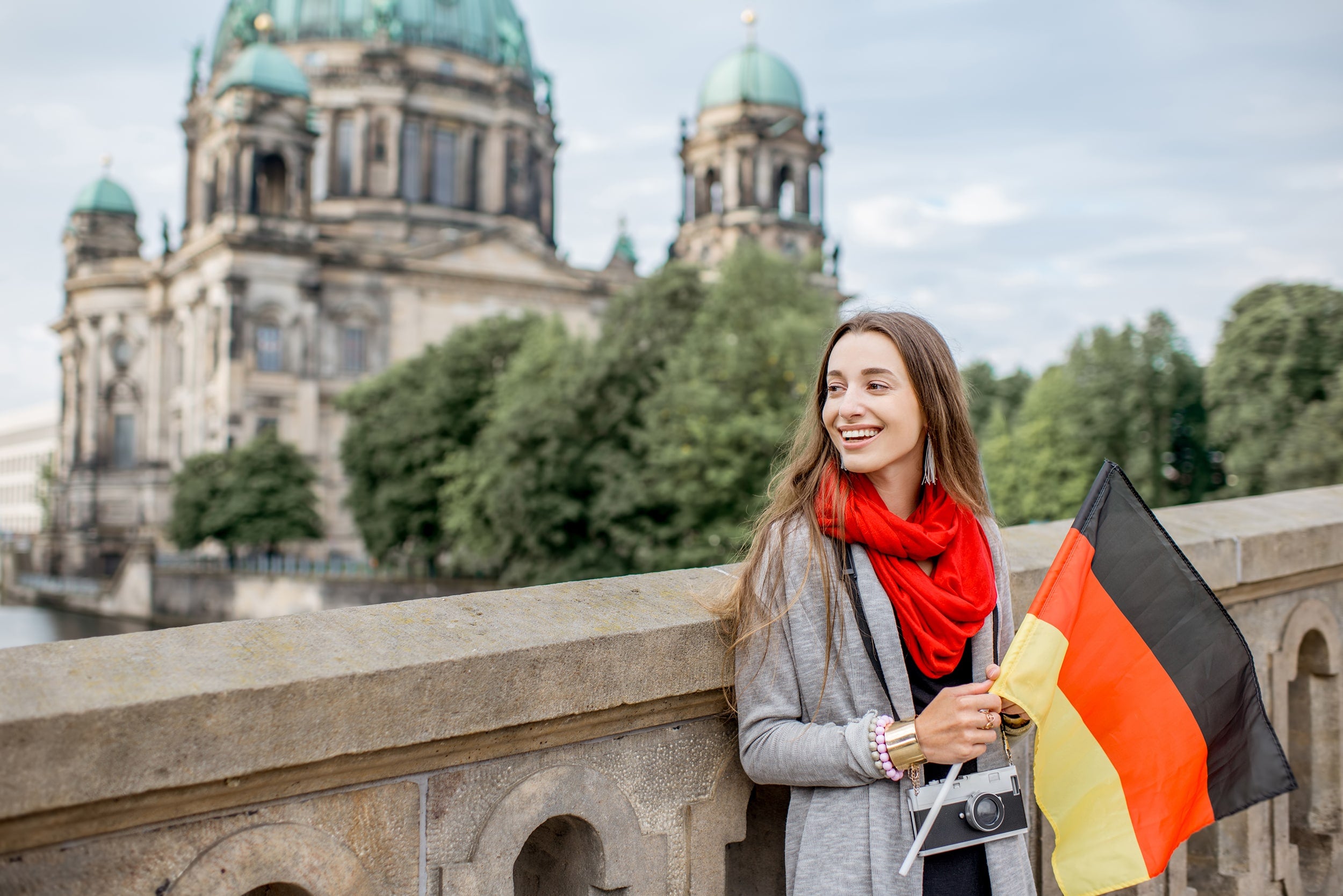 Georgia Southern student studying abroad in Germany standing in front of a building holding a German flag.