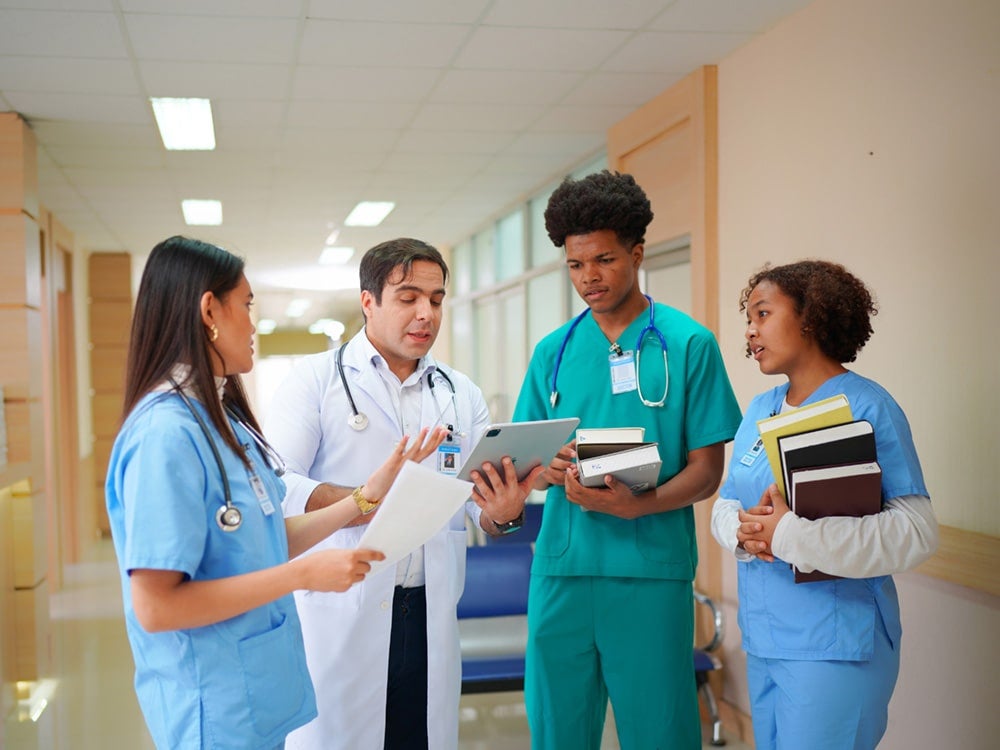 Group of Georgia Southern EagleMed students speaking with a doctor in a hospital setting.