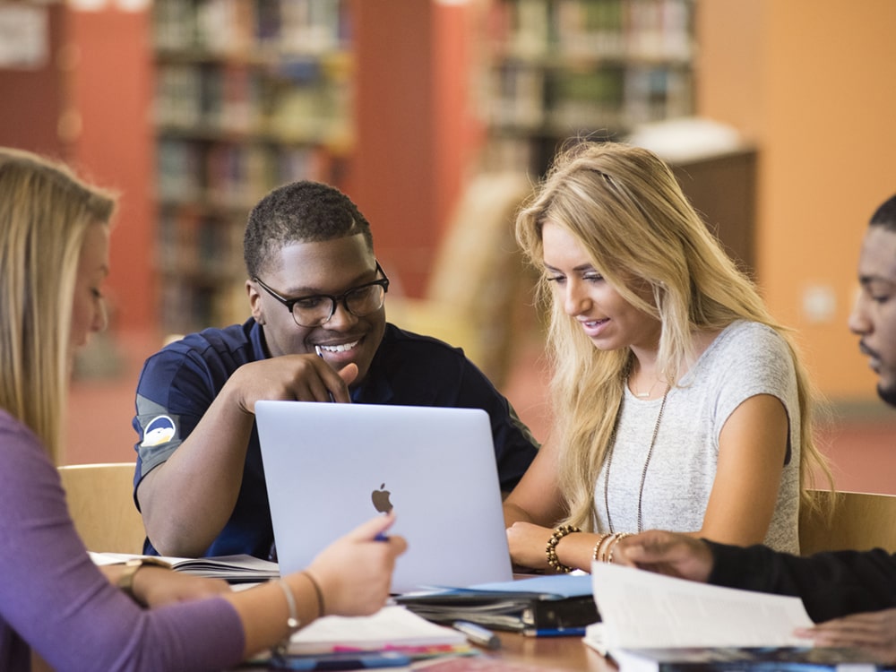 A group of students from Georgia Southern's M.A. in Professional Communication and Leadership program collaborate on an assignment in a campus library