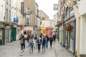 A group of students walk down a shop-lined street in Wexford.